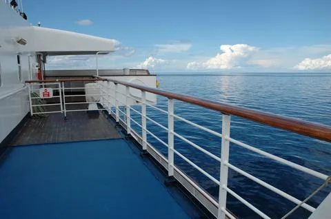 Ship deck with railing overlooking calm blue ocean Stock Photos