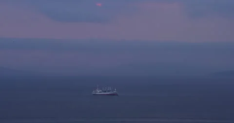 Ship drifts on sea and violet twilight sky reflects on water Vídeo Stock 320042345