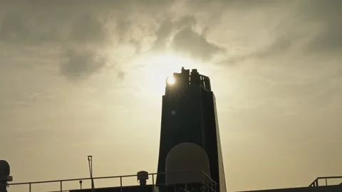 Ship funnel and deck silhouette backlit by sun in hazy sky Stock Footage 337913868