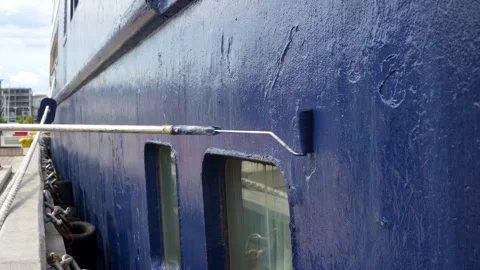 Ship hull maintenance with paint roller applying protective coating on old blue Stock Footage 335272749