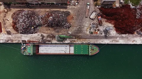 Ship loading cargo at a busy port with waste materials nearby 動画素材 338324579