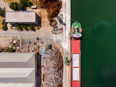 Ship loading cargo at a dock with industrial area and waste site in the bac.. Stock Photos