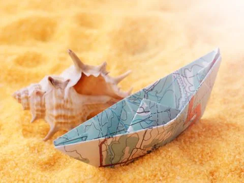Ship model from a paper map on the sand, seashell Stock Photos