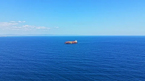 Ship navigates through a clear blue ocean on a sunny day with few clouds in the Stock Footage 344809816
