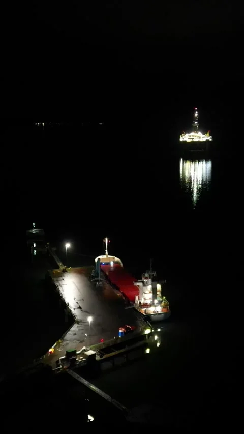 Ship parked on docks port night aerial dark with oil rig on background flying Stock Footage 281501095