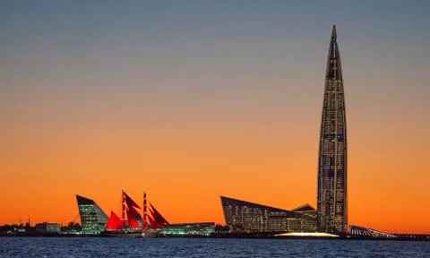 A ship with red sails at sunset on the background of a beautiful city and a Fotos Stock