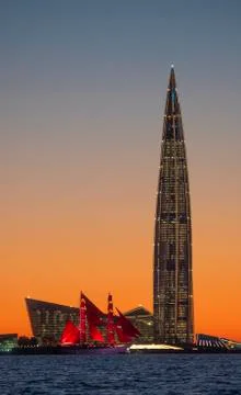 A ship with red sails at sunset on the background of a beautiful city and a Stock Photos