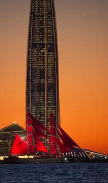 A ship with red sails at sunset on the background of a beautiful city and a Stock Photos