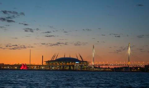 A ship with red sails at sunset on the background of a beautiful city and a Fotos Stock