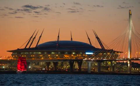 A ship with red sails at sunset on the background of a beautiful city and a Fotos Stock