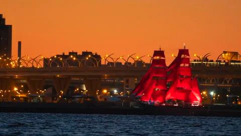 A ship with red sails at sunset on the background of a beautiful city and a Stock Photos