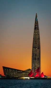 A ship with red sails at sunset on the background of a beautiful city and a Fotos Stock