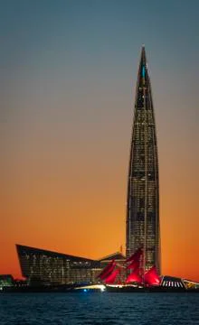 A ship with red sails at sunset on the background of a beautiful city and a Stock Photos