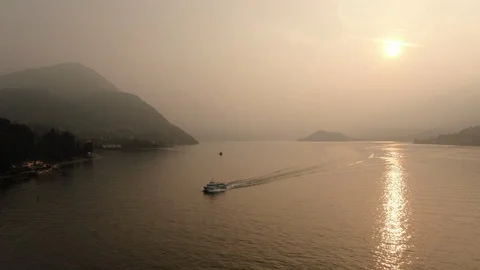 Ship sailing against backdrop of sunset on Lake Como. Sun is reflected in water Stock Footage