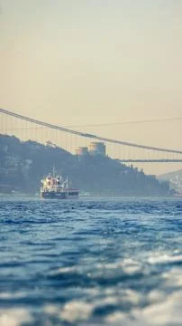 Ship sailing under the Bosphorus Bridge with Rumeli Fortress in the backgroun Stock Photos