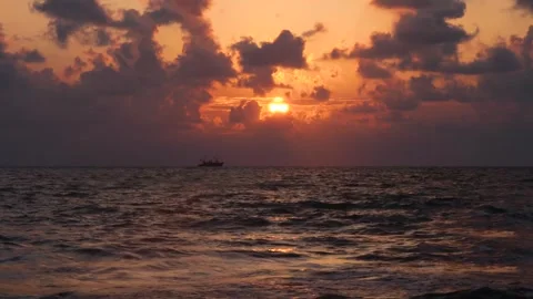 A ship sails across the ocean at sunset with dark clouds Vidéo 286056712