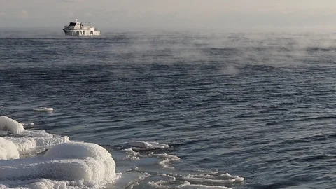 The ship sails on the lake Baikal floating from frost along the icy coast in Stock Footage 100714322