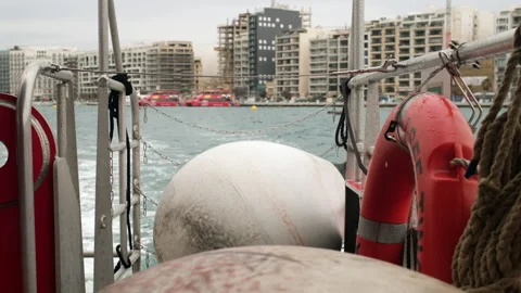 Ship Stern View Focused on Large White Mooring Fenders with Blurred Cityline Stock Footage 330860394