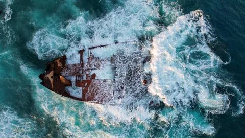 A ship stranded washed by waves near the shore, footage taken from the air on a  Stock Photos