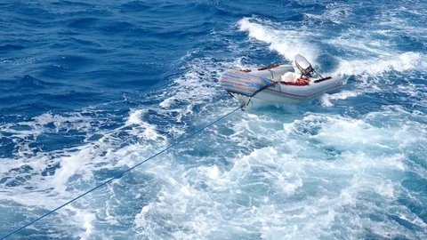 Ship tows a small boat behind it connected by a thick rope. 스톡 동영상 84835742