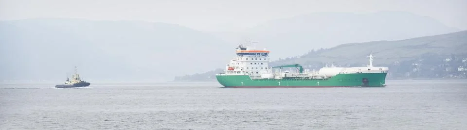 Ship transporting floating storage container platform in sea followed by tugboat Stock Photos