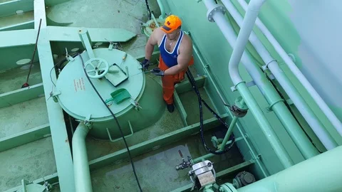 Ship worker in orange helmet colours modern oil tanker pipes Stock Footage 118358317