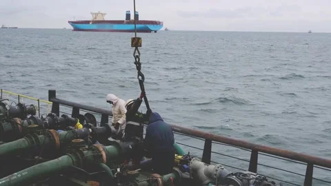 Ship workers in helmets connect tanker product pipelines Stock Footage 131605673