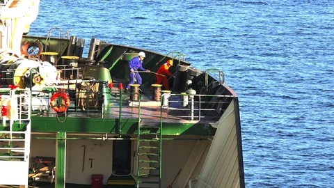 Ship workers pull and fix long rope with oil transfer hose Stock Footage 113457139