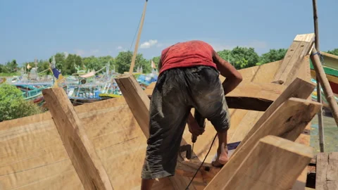 A shipbuilder is drilling the triangular section of a traditional wooden boat Stock Footage 253133590