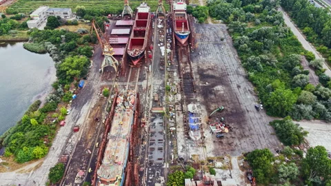 Shipbuilding occurs in a busy yard with multiple vessels and tools present Stock Footage 341108699