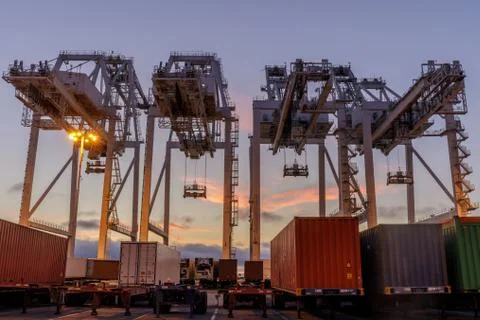 Shipping Container Cranes and Trucks with Sunset Sky in the Port of Oakland Stock Photos