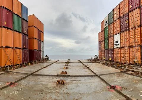 Shipping Containers on Cargo Ship Deck with Central Perspective and Dramatic Sky Foto stock
