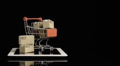 Shipping paper boxes inside Red shopping cart trolley on tablet Stock Photos