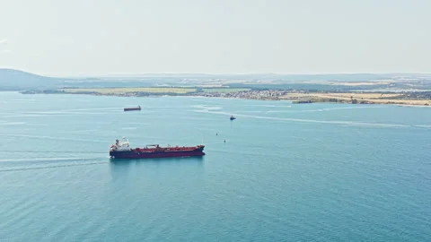 Shipping vessels navigate through calm waters near a coastal area with visible Stock Footage 341377848