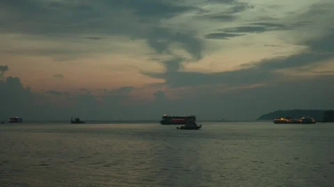 Ships and boats with lights float on calm waters at dusk under a moody, Vídeos de archivo 291230975