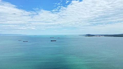 Ships float in the ocean while clouds drift above the water on a clear day near Stock Footage 340178392
