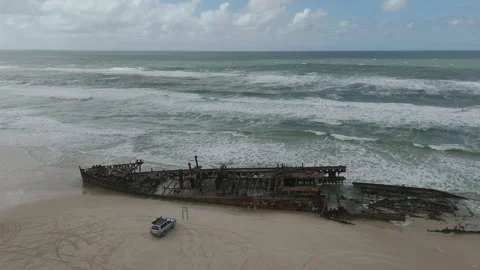Shipwreck on sandy beach with waves and small vehicle Stock Footage 341617696