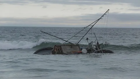 Shipwrecked boat tumbling through the waves at dusk Stock Footage