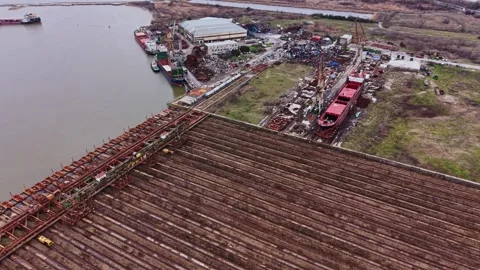Shipyard under construction with cargo vessels waiting on the water Stock Footage 337941476