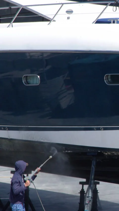 Shipyard Worker Pressure Washing the Hull of a Luxury Yacht Stock Footage 338420080