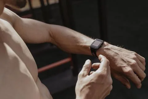 Shirtless athlete using smartwatch while resting workout. Stock Photos