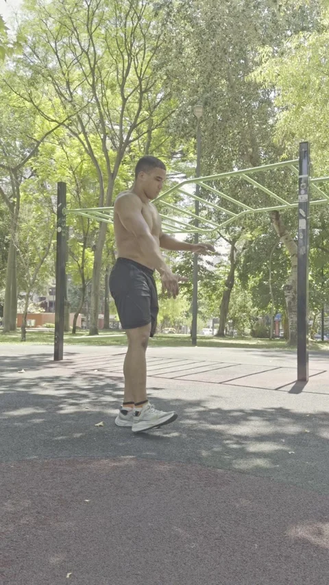 Shirtless athletic man doing one-leg pistol squats at an outdoor gym. Video stock 326683669