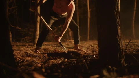 Shirtless bald Man Digging a Grave with a Shovel in the forest Video stock 259112629
