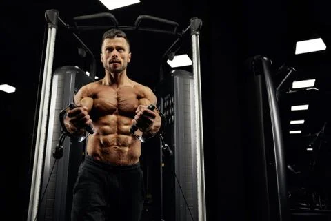 Shirtless bodybuilder doing low cable crossover exercise. Stock Photos