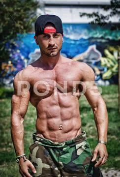 Shirtless bodybuilder showing torso muscles, abs, pecs and arms outdoors Stock Photos