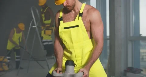 Shirtless builder in overall and hardhat prepare cement in bucket. Stock Footage 153408603