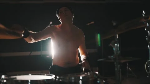 Shirtless drummer playing drums energetically on stage Stock Footage 329170082
