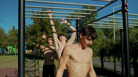 Shirtless Generation Z boy doing dynamic pull ups on monkey bars at the park. Stock Footage 346141537