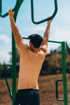 Shirtless guy training on pull ups on on chin up bar 스톡 사진