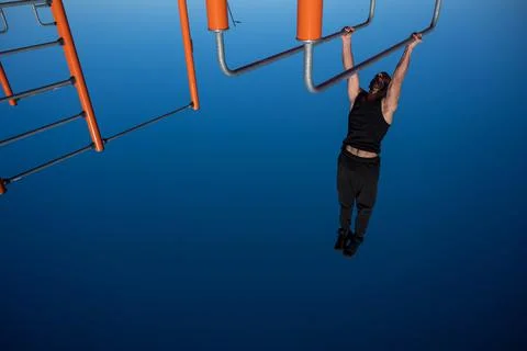 Shirtless man doing handstand on parallel bars at sports ground. 写真素材